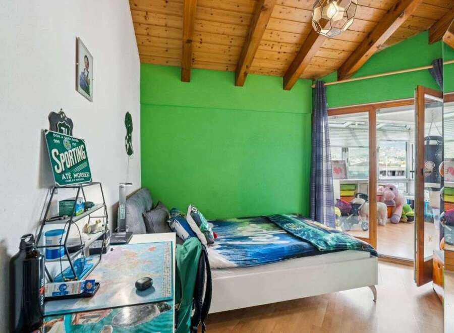 This vibrant bedroom features a comfortable white bed with a striking blue and green comforter, set against a lively green accent wall.