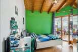 This vibrant bedroom features a comfortable white bed with a striking blue and green comforter, set against a lively green accent wall.