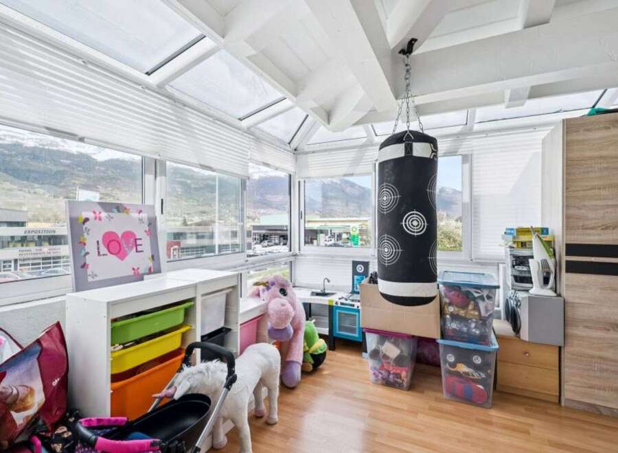 This sunroom offers a versatile space for play and relaxation, featuring a punching bag and a toy kitchen.