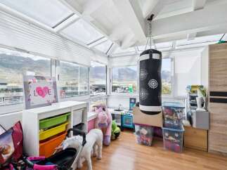This sunroom offers a versatile space for play and relaxation, featuring a punching bag and a toy kitchen.