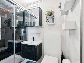 Experience modern luxury in this meticulously designed bathroom, featuring a sleek vanity with a wave-patterned facade and a stylish black faucet.
