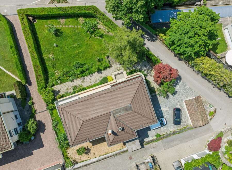 Discover this stunning aerial view of a modern home featuring a spacious, well-maintained lawn and a neatly trimmed hedge.