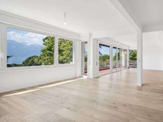 Experience breathtaking panoramic views from this spacious living area, featuring expansive windows that showcase stunning mountain and lake vistas.