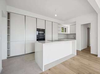 Discover this modern, minimalist kitchen featuring sleek white cabinetry and integrated appliances, including a built-in oven.