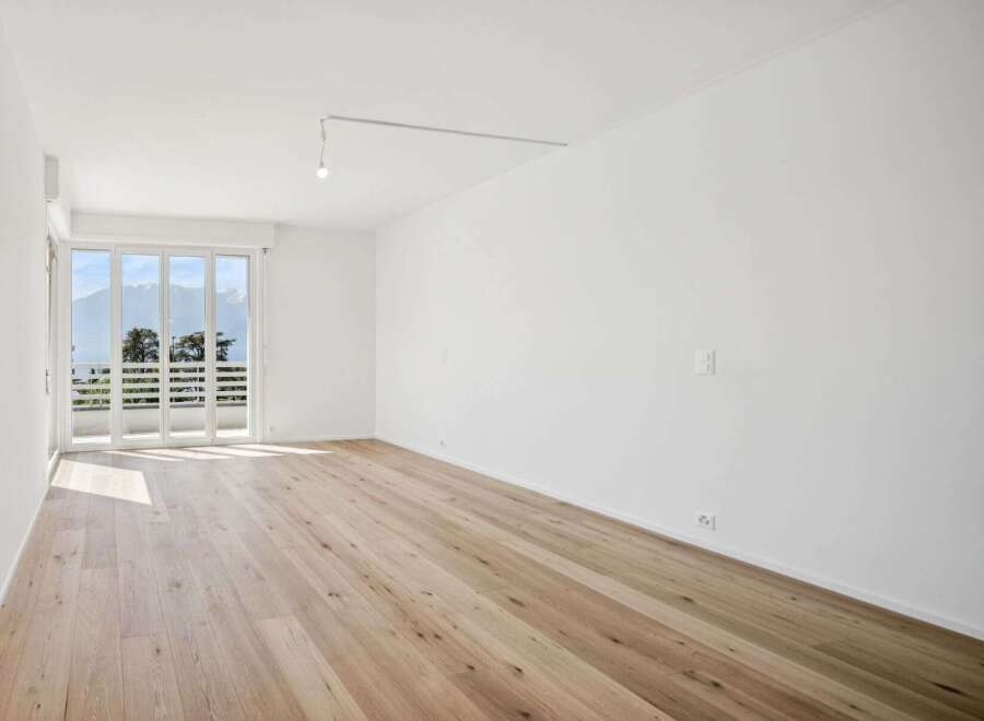 Experience modern living in this bright and airy room featuring a stunning panoramic view of the mountains through expansive glass doors.