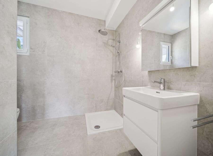 This modern bathroom features a spacious walk-in shower with a rainfall showerhead, perfect for a relaxing experience.