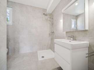 This modern bathroom features a spacious walk-in shower with a rainfall showerhead, perfect for a relaxing experience.