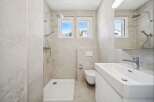 This modern bathroom features a spacious walk-in shower with a rainfall showerhead and a separate handheld shower.