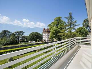 Enjoy breathtaking panoramic views from this stunning balcony, overlooking a serene lake and majestic mountains.