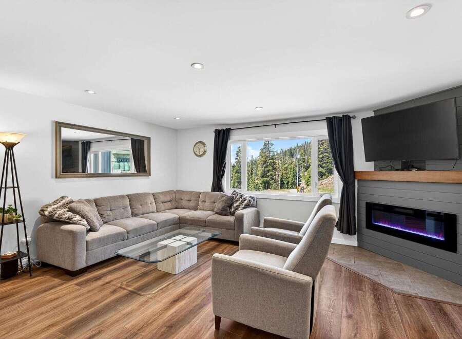 Experience breathtaking mountain views from this stunning living room, featuring a spacious sectional sofa and a modern electric fireplace.