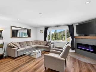 Experience breathtaking mountain views from this stunning living room, featuring a spacious sectional sofa and a modern electric fireplace.