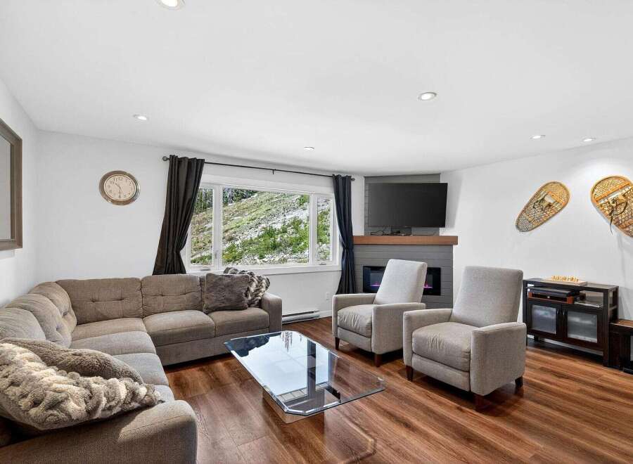 Experience breathtaking mountain views from this cozy living room, featuring a large sectional sofa and a modern fireplace.