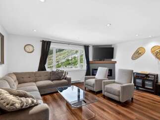 Experience breathtaking mountain views from this cozy living room, featuring a large sectional sofa and a modern fireplace.