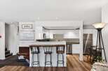 Experience a modern retreat with this stunning kitchen featuring sleek white cabinetry, a stylish subway tile backsplash, and a convenient breakfast bar with seating.