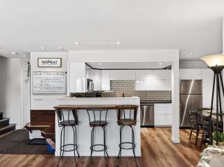 Experience a modern retreat with this stunning kitchen featuring sleek white cabinetry, a stylish subway tile backsplash, and a convenient breakfast bar with seating.