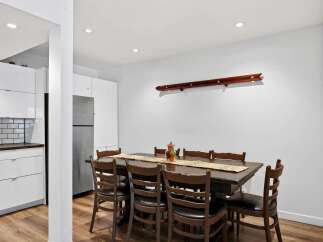 This spacious dining area features a large, dark wood table with eight matching chairs, perfect for family gatherings.