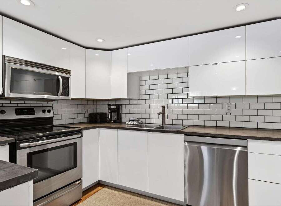 Discover this modern kitchen featuring sleek white cabinetry and a stylish subway tile backsplash.