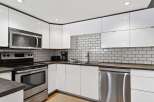 Discover this modern kitchen featuring sleek white cabinetry and a stylish subway tile backsplash.