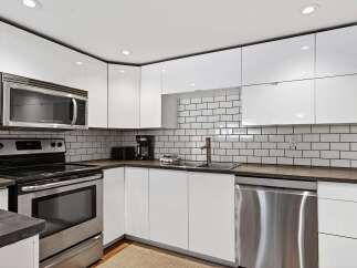 Discover this modern kitchen featuring sleek white cabinetry and a stylish subway tile backsplash.