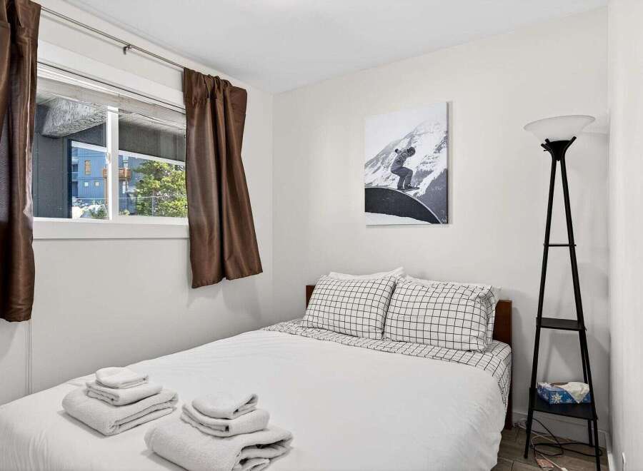 This cozy bedroom features a comfortable bed with crisp white linens and stylish checkered pillowcases.
