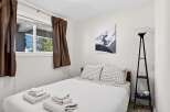 This cozy bedroom features a comfortable bed with crisp white linens and stylish checkered pillowcases.