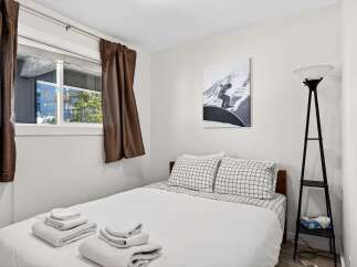 This cozy bedroom features a comfortable bed with crisp white linens and stylish checkered pillowcases.