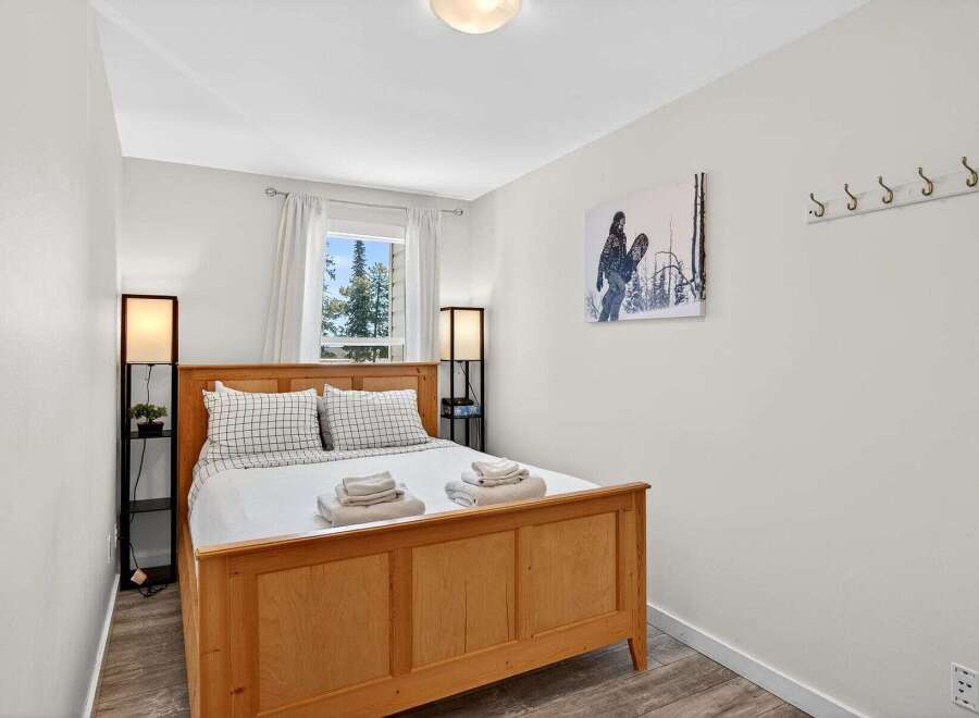 This cozy bedroom features a warm wooden bed frame, complemented by crisp white bedding and plaid accent pillows.