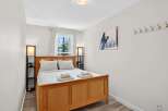This cozy bedroom features a warm wooden bed frame, complemented by crisp white bedding and plaid accent pillows.