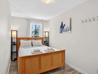 This cozy bedroom features a warm wooden bed frame, complemented by crisp white bedding and plaid accent pillows.