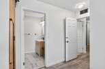 Step into a bright and airy hallway featuring a modern bathroom with a sleek vanity and marble-tiled floor.
