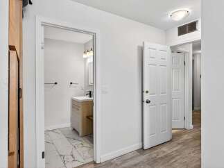 Step into a bright and airy hallway featuring a modern bathroom with a sleek vanity and marble-tiled floor.