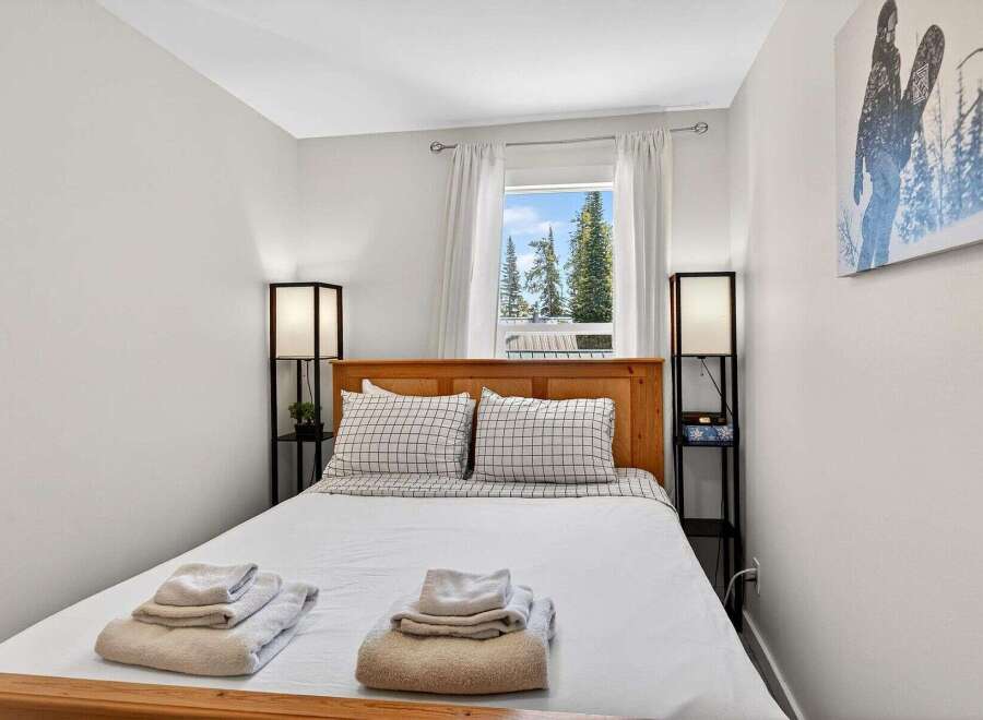 Experience comfort and style in this inviting bedroom, featuring a cozy queen-size bed adorned with crisp white linens and charming plaid pillows.