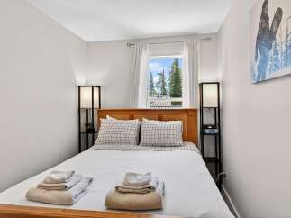 Experience comfort and style in this inviting bedroom, featuring a cozy queen-size bed adorned with crisp white linens and charming plaid pillows.
