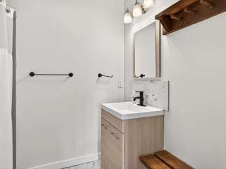 This modern bathroom features a sleek vanity with a light wood finish, complemented by a minimalist black faucet and a tiled backsplash.