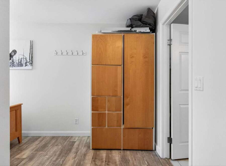 This hallway features a tall wooden cabinet with multiple storage compartments, perfect for organizing your belongings.