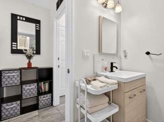 This modern bathroom features a sleek vanity with a light wood finish and a white countertop, complemented by a black faucet and a tiled backsplash.