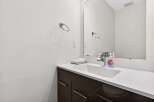 This modern bathroom features a sleek vanity with dark cabinetry and a white countertop, complemented by a minimalist sink and chrome faucet.