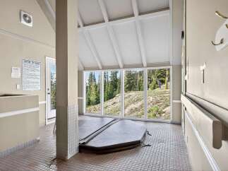 Enjoy a relaxing soak in this indoor hot tub room, featuring a large, covered spa with stunning views of the surrounding forest and ski slopes.