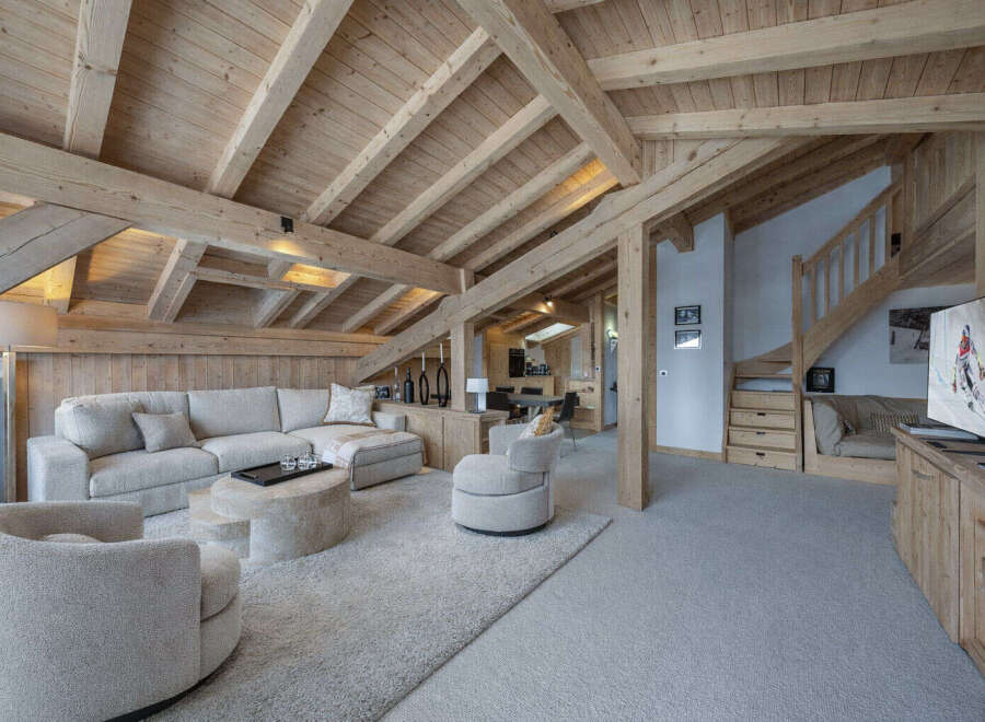 Experience luxurious mountain living in this stunning chalet featuring a spacious open-plan living area with a large sectional sofa and a unique stone coffee table.