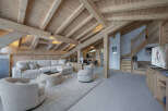 Experience luxurious mountain living in this stunning chalet featuring a spacious open-plan living area with a large sectional sofa and a unique stone coffee table.
