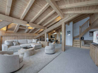 Experience luxurious mountain living in this stunning chalet featuring a spacious open-plan living area with a large sectional sofa and a unique stone coffee table.