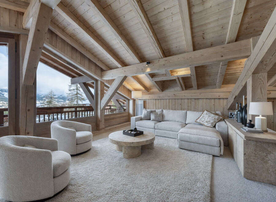 Experience luxurious mountain living in this stunning chalet living room, featuring a plush sectional sofa and cozy armchairs perfect for relaxing.