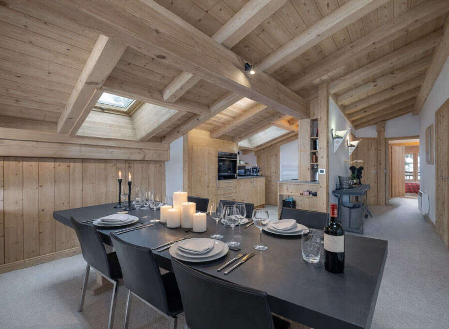 Experience rustic charm and modern comfort in this stunning dining area, featuring a large wooden-beamed ceiling and a cozy, wood-paneled wall.