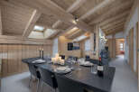 Experience rustic charm and modern comfort in this stunning dining area, featuring a large wooden-beamed ceiling and a cozy, wood-paneled wall.