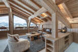 Experience luxurious alpine living in this stunning chalet living room, featuring exposed wooden beams and a vaulted ceiling that creates an airy, open atmosphere.