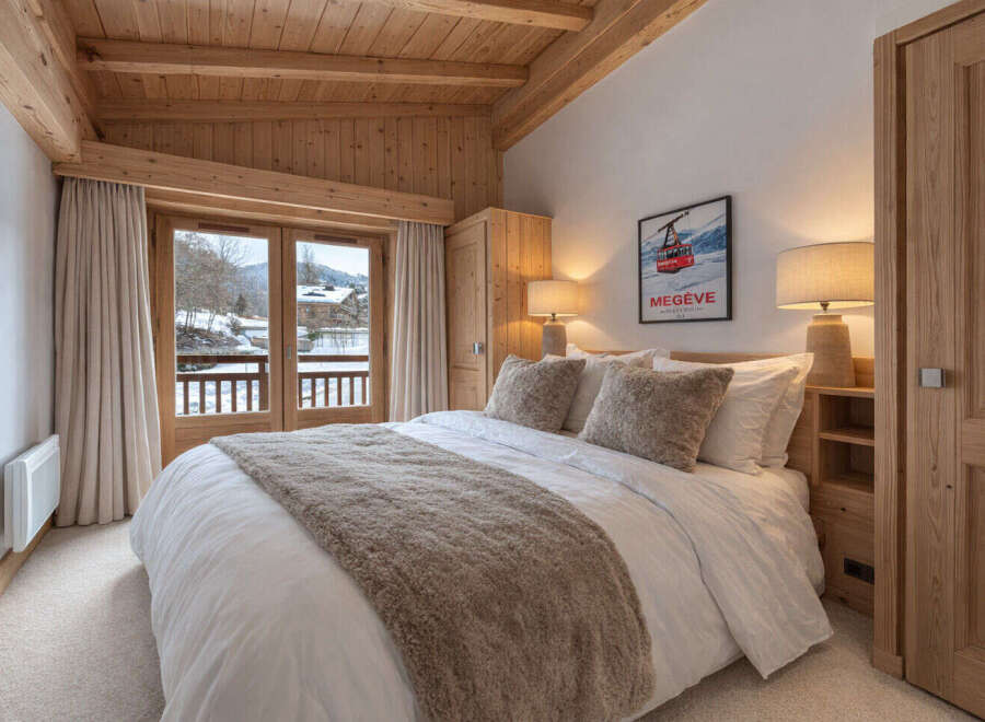 Experience alpine luxury in this charming bedroom featuring a cozy bed adorned with plush pillows and a warm throw.