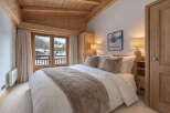 Experience alpine luxury in this charming bedroom featuring a cozy bed adorned with plush pillows and a warm throw.
