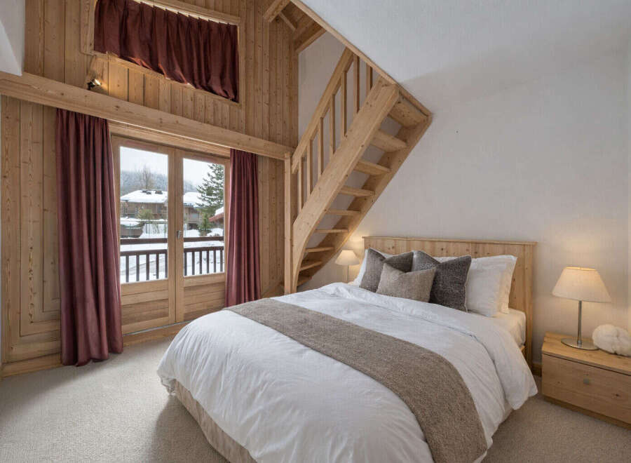 Experience cozy mountain living in this charming bedroom featuring a wooden staircase leading to a loft.