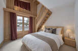 Experience cozy mountain living in this charming bedroom featuring a wooden staircase leading to a loft.