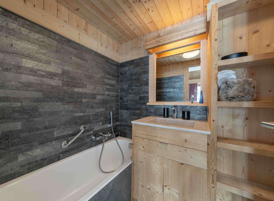 Experience rustic charm in this bathroom featuring a deep soaking tub set against a striking slate tile wall.